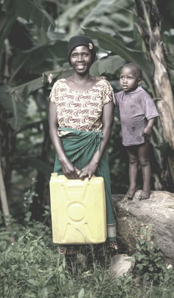 A smiling poor woman grabbing a plastic container and standing along with a kid
