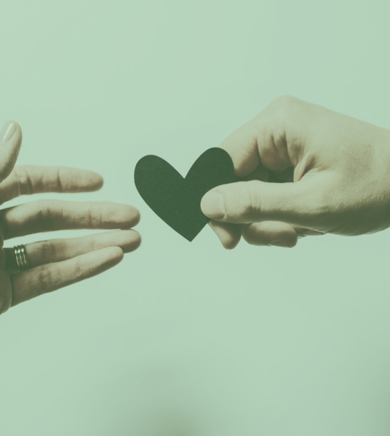 close-up of two hands exchanging heart shaped piece of paper