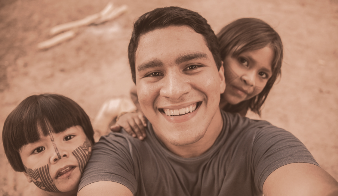 Selfie d'un homme souriant avec un petit garçon et une petite fille derrière lui.
