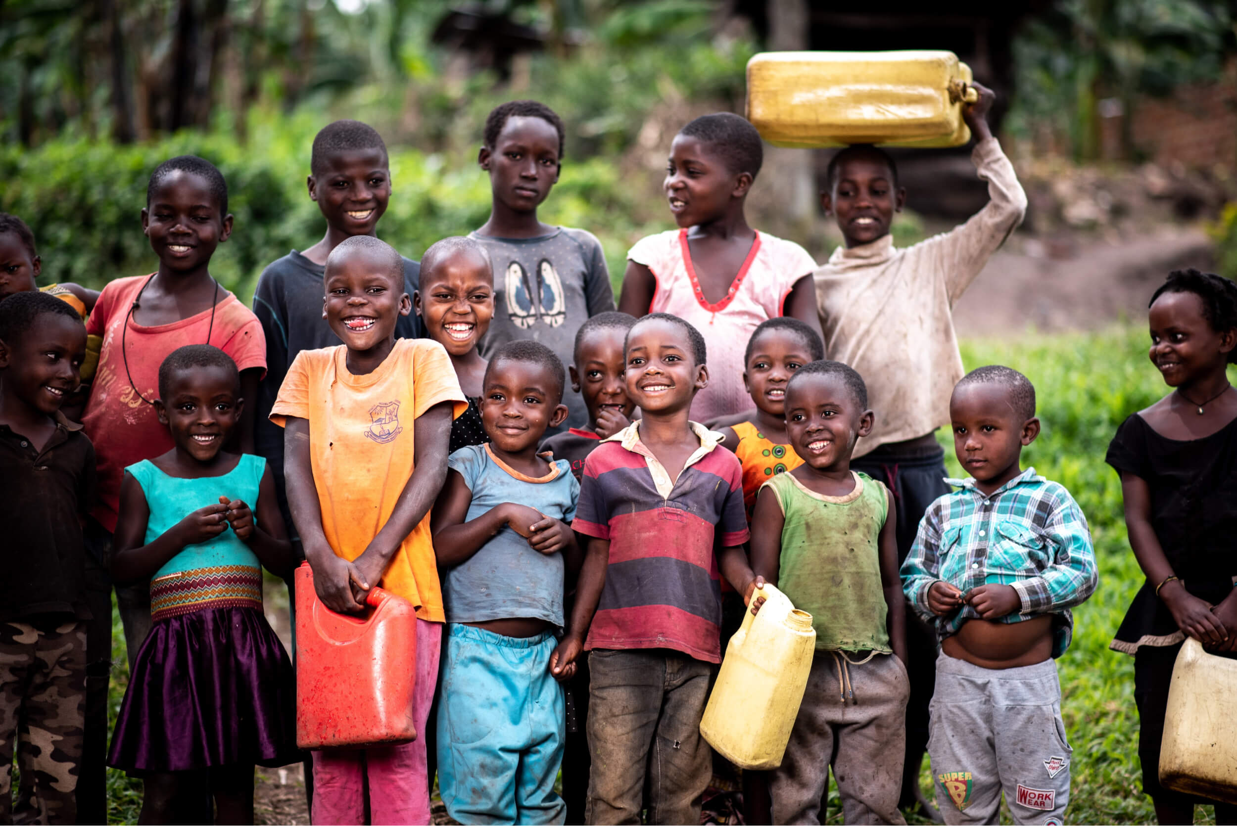group of kids smiling together, few holding containers