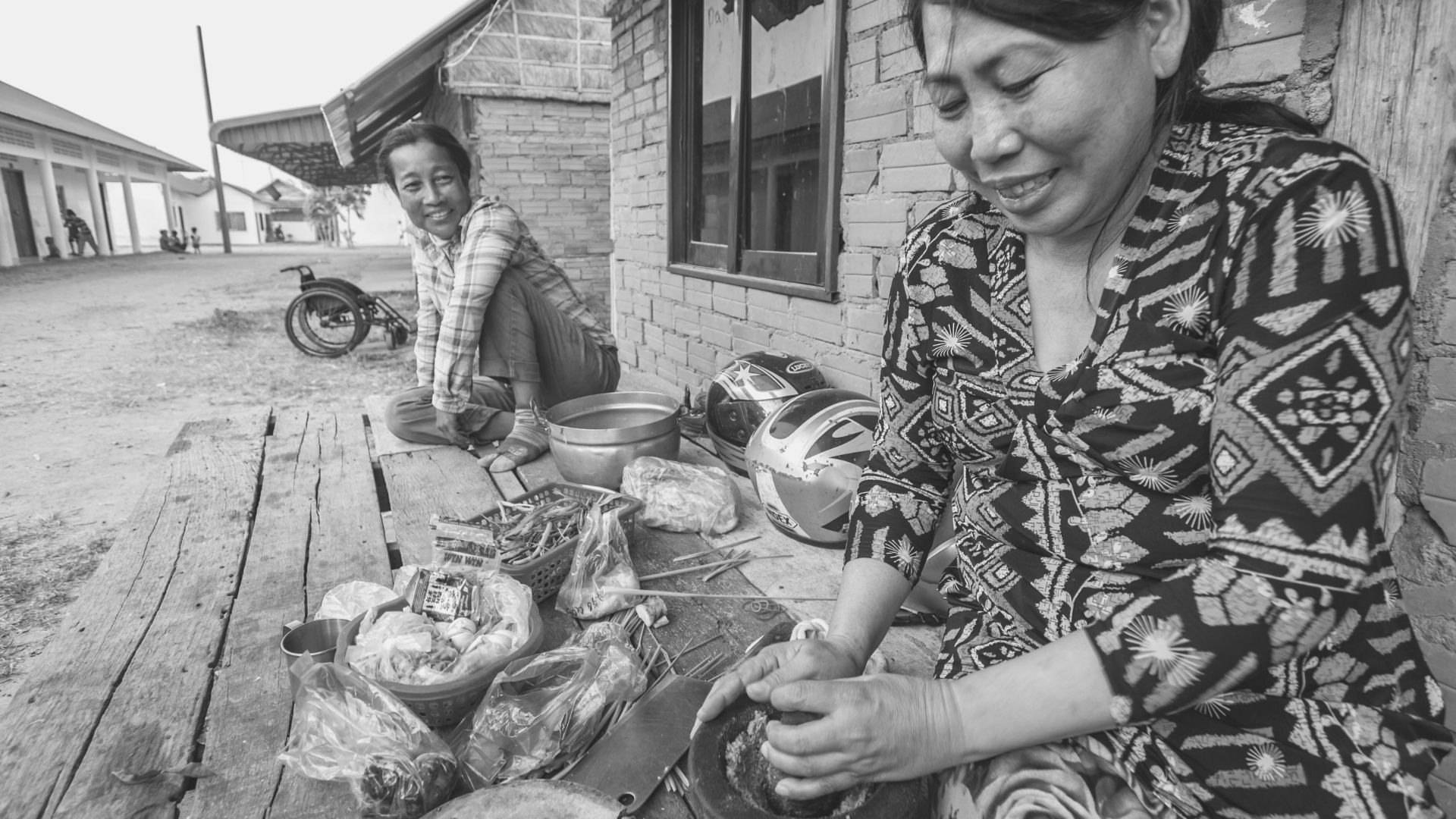 two woman smiling and working together on wooden bench