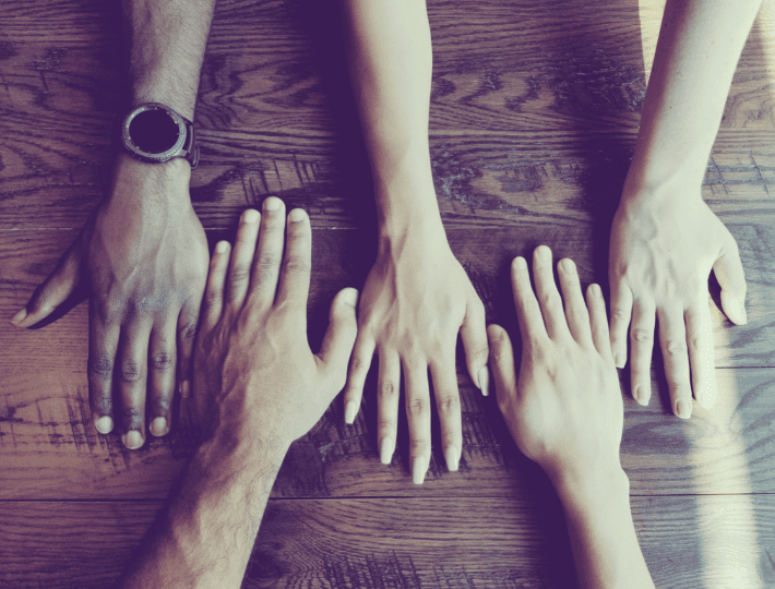 group of hands of different people on table showing diversity