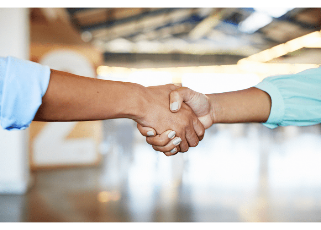 Photo shows a handshake between two people, zoomed in to focus on the hands.