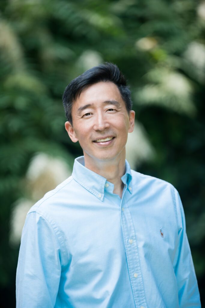 Photo de Ken Shigamatsu, un homme japonais, portant une chemise bleu clair, souriant.